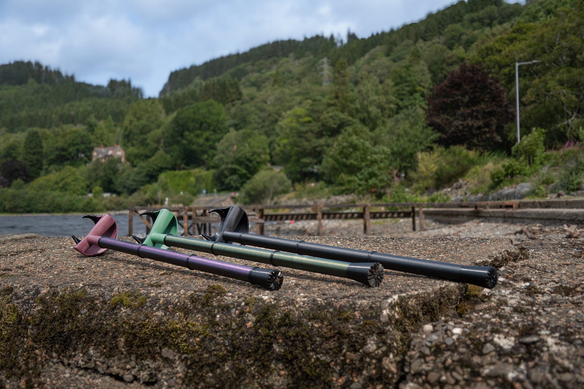 Three Ergonomic Walking Sticks displayed on a riverbank